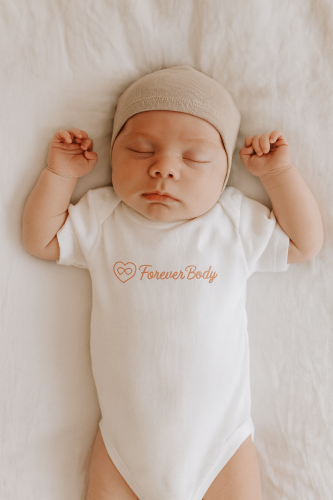 a picture of a newborn sleeping. wearing a foreverbody babybody